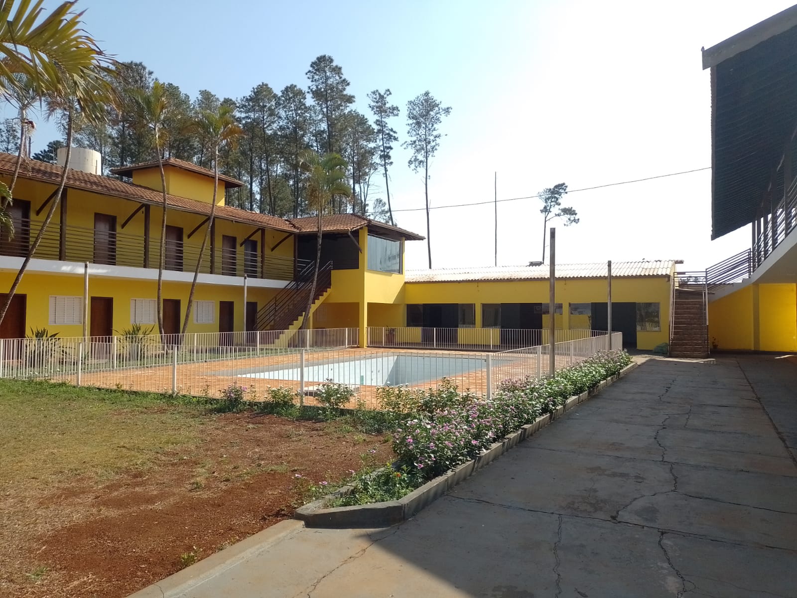 Vista ampla da área externa com jardim, piscina e edifícios