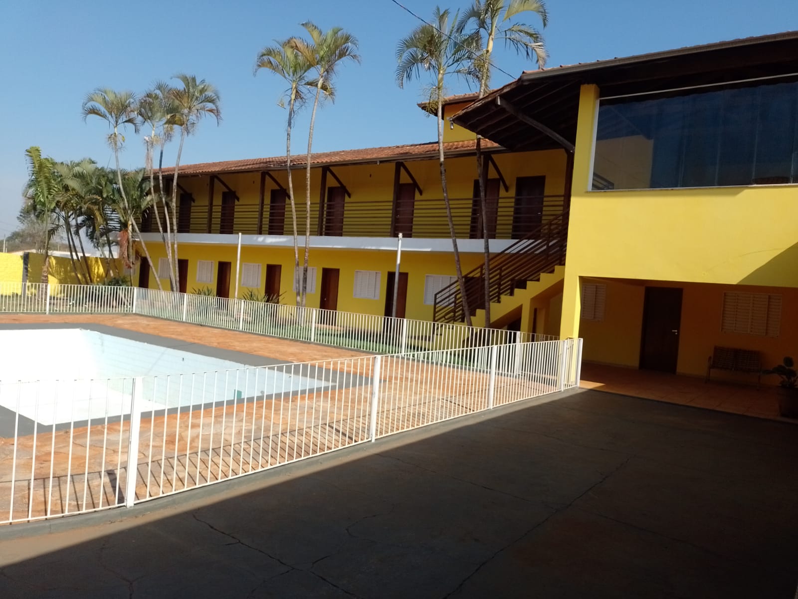 Piscina cercada com prédio de dois andares ao fundo